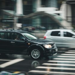 black suv beside grey auv crossing the pedestrian line during daytime